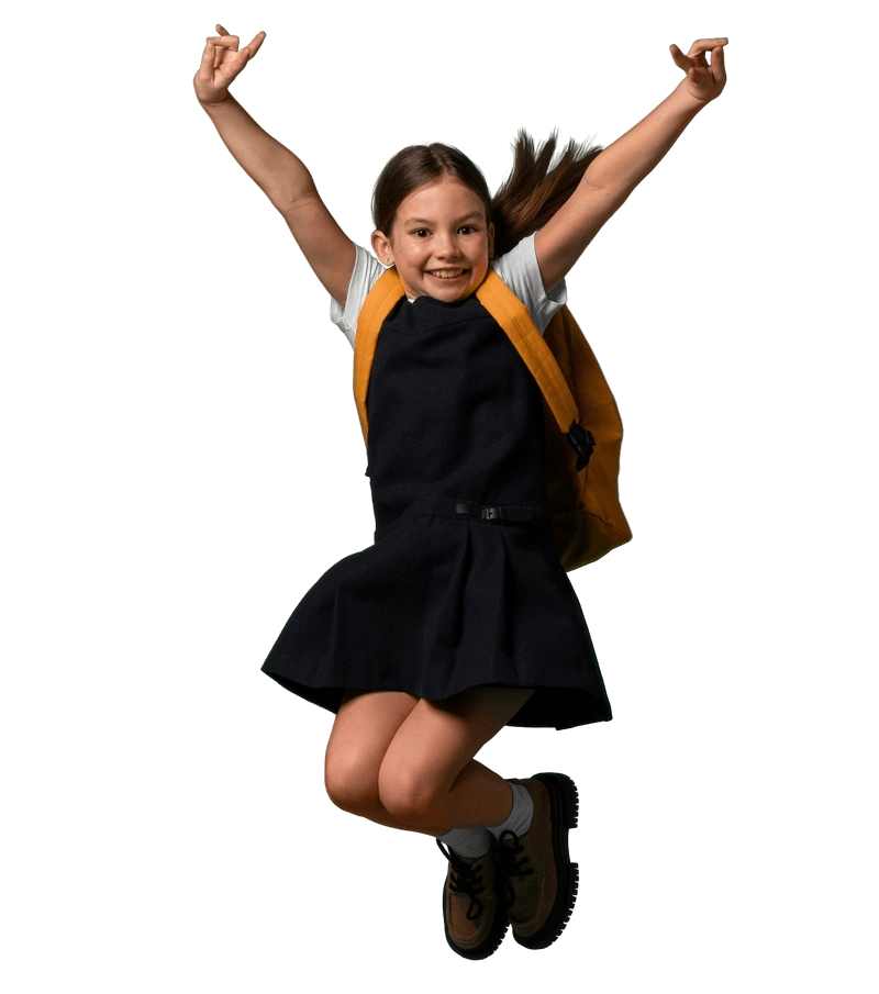 Pupil in school uniform jumping with arms raised